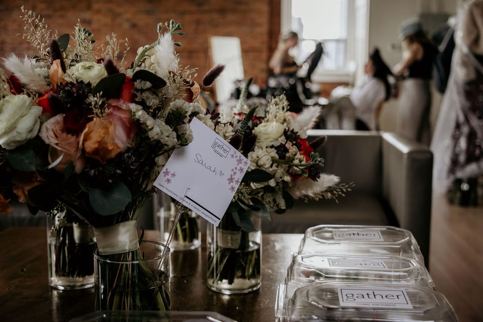 Bridal bouquets and floral centrepieces waiting on a table at a brick venue.
