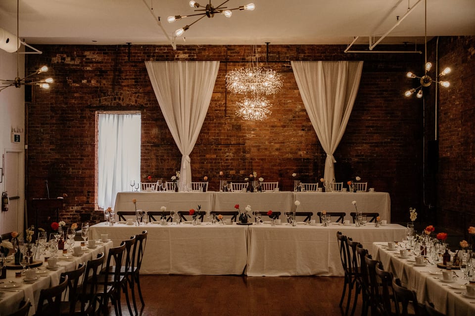 Reception head table with a draped backdrop and candlelit place settings.