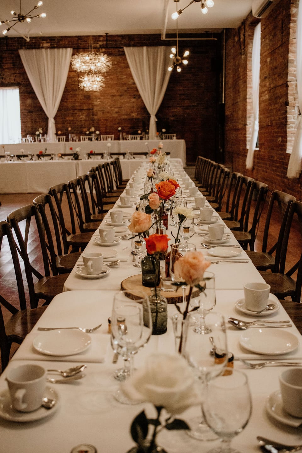 Reception tables set for dinner in a warm brick hall.