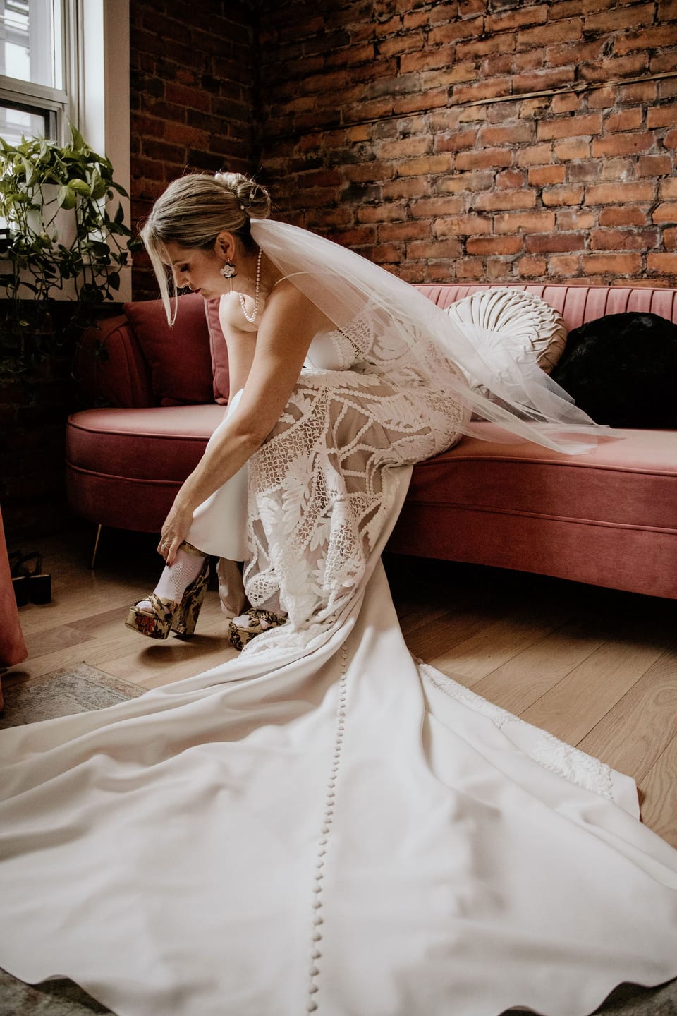 Bride from behind, her full gown trailing as she walks through the venue.